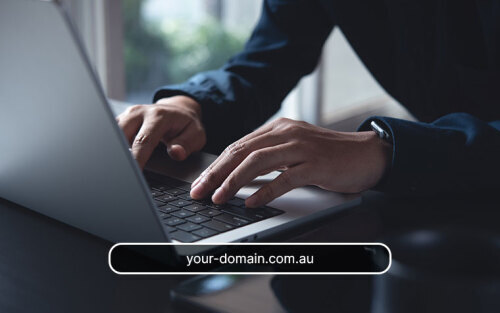 Hands typing on a laptop with a domain name in a search box overlaying