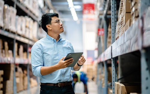 Warehouse manager use a digital tablet to check the stock inventory on shelves in large warehouses